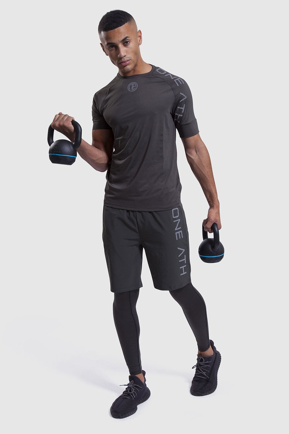 Man lifting kettlebells in training tops and shorts