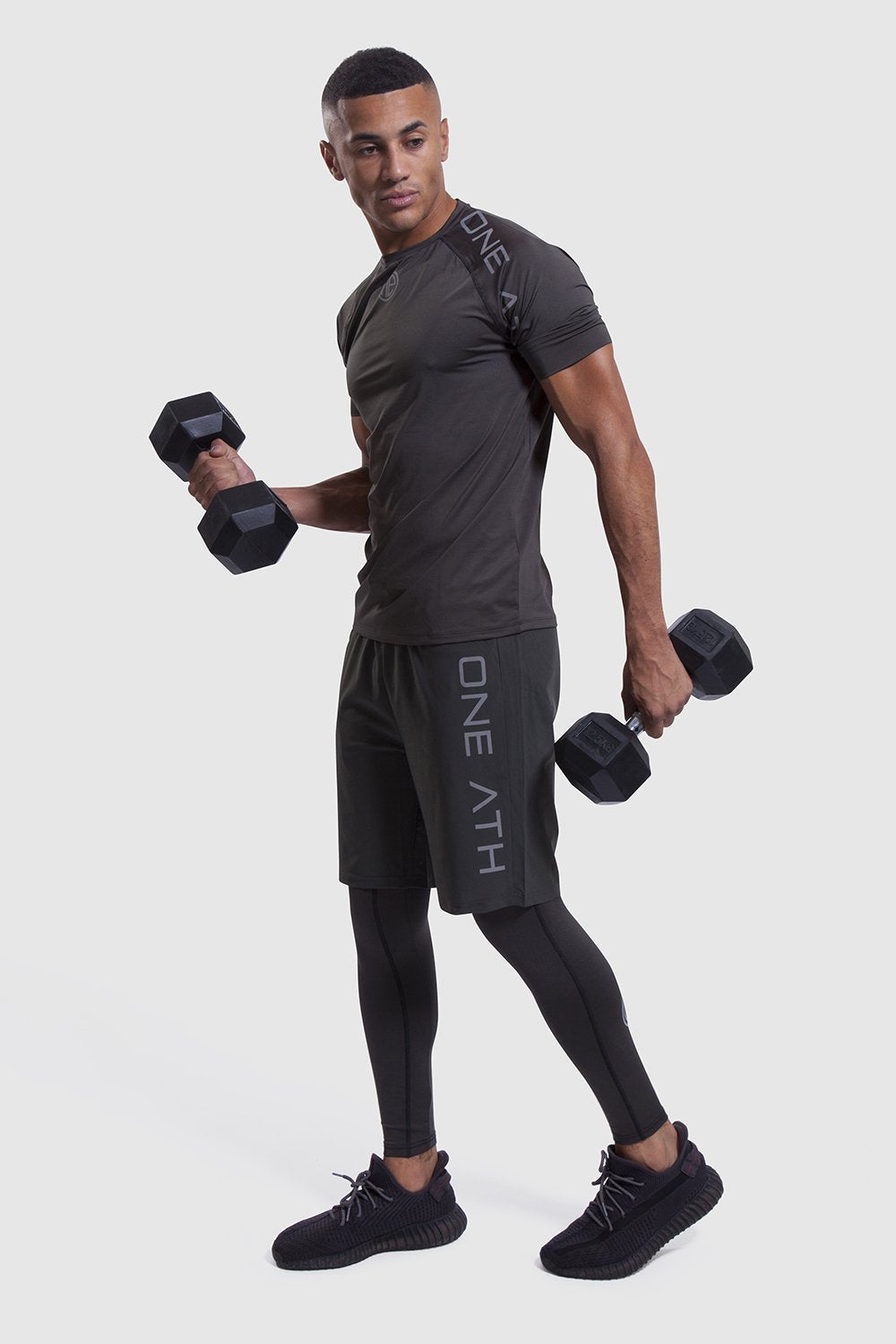 Person lifting 2 dumbbells in mens gym t-shirt and shorts